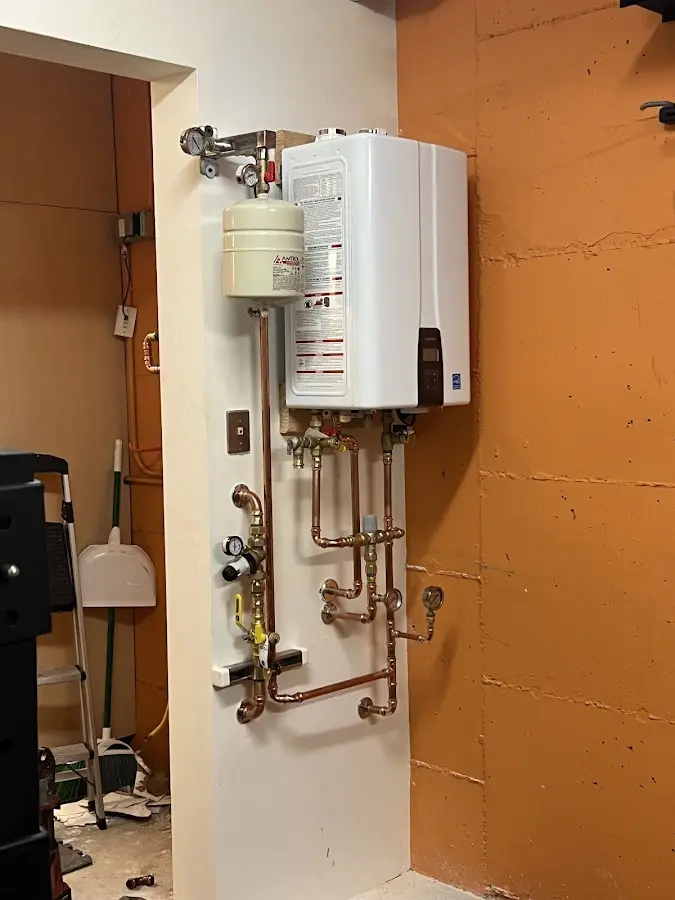Plumbing technician inspecting water heater connections in New Albany